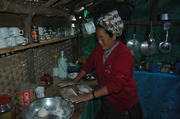 In the kitchen area, Dawa is helping with the preparation of the Tibetan Bread. It is first mixed, then rolled, cooked on a dry pan and finally puffed on the fire.